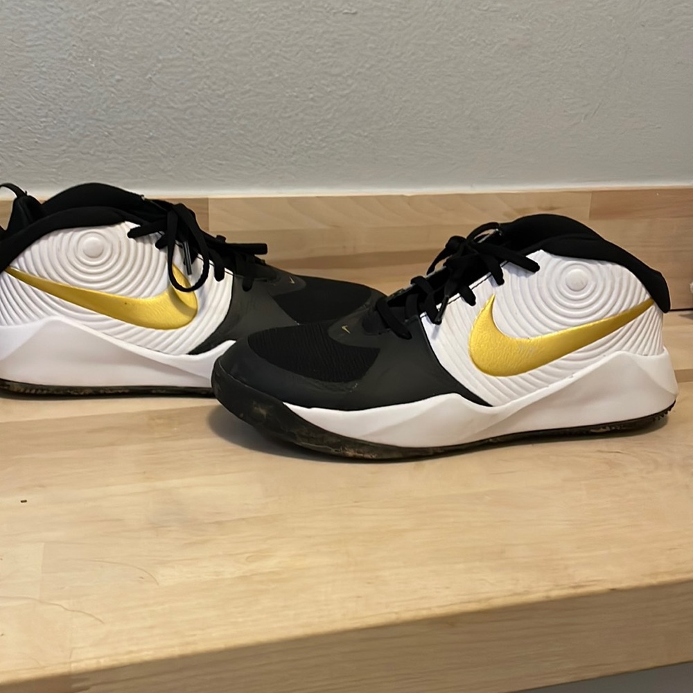 White and black Nike tennis shoes with gold swish